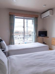 名户YANBARU STAY ちゅら宿的酒店客房设有两张床和窗户。