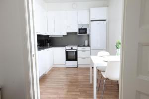 赫尔辛基2ndhomes Cozy and Quiet 2BR Apartment by the Esplanade Park的白色的厨房配有白色的橱柜和桌子