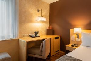 里斯本都市HF菲尼克斯酒店的客房设有一张桌子、一把椅子和一张床