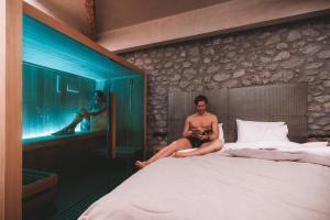 卡兰巴卡Tsikeli Boutique Hotel Meteora - Adults Friendly的坐在房间里床边的人