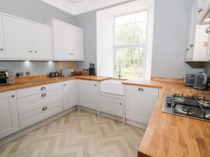 梅奈布里奇Flat 2 Tyn Y Caeau的厨房铺有木地板,配有白色橱柜。