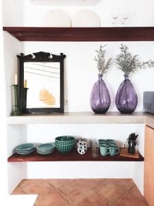 贝雅Lobeira - Centenary country house and gardens的三个紫花瓶坐在架子上,摆盘子