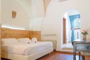 Villa CastelliMasseria Le Lamie的一间卧室配有一张床、一张桌子和一个窗户。