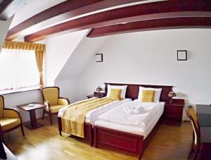 TopoľčiankyHradná stráž Hotel&Apartments s privátnym wellness的一间卧室配有一张床和两把椅子