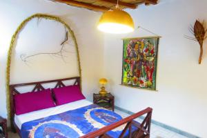 KafountineKASA HIBISCUS的卧室配有一张床,墙上挂有绘画作品