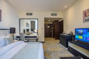 阿布扎比Grand Villaggio Hotel Abu Dhabi的酒店客房设有一张大床和一台电视。