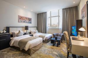 阿布扎比Grand Villaggio Hotel Abu Dhabi的酒店客房配有两张床和一张书桌
