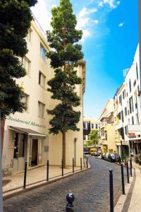 丰沙尔Residencial Monaco的一座建筑旁边的鹅卵石街道上的一棵树