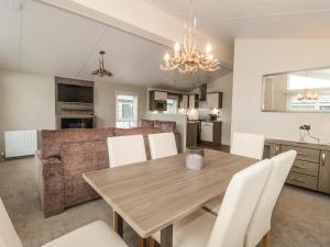 利明顿Amethyst Lodge的用餐室以及带木桌和白色椅子的客厅。
