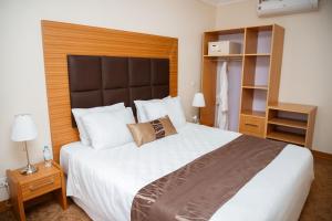 基加利Ndaru Luxury suites的卧室配有一张白色大床和木制床头板