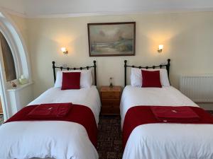 斯凯格内斯Knighton Lodge的配有红色和白色床单的客房内的两张床