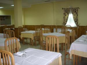 Vega de Espinareda奎斯塔旅馆的用餐室配有白色的桌子和木椅