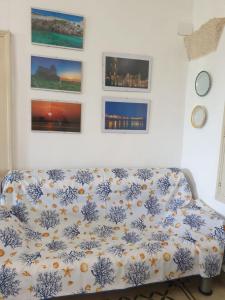 圣卡特琳娜迪纳德Masseria Vivi il Salento的客厅的沙发,墙上挂有绘画作品