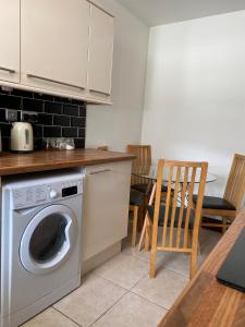 斯旺西Cosy 2 Bed Flat 1 in Swansea - Home away from Home的厨房配有洗衣机和桌子