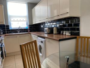 斯旺西Cosy 2 Bed Flat 1 in Swansea - Home away from Home的厨房配有洗衣机和烘干机