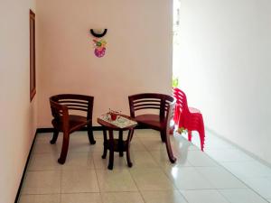 PosoRedDoorz @ Makarios Hotel Poso的一间设有椅子和桌子的房间,墙上有时钟