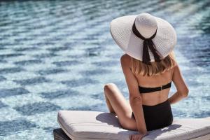 法里拉基埃斯佩罗斯宫度假酒店的坐在游泳池旁的戴帽子的女人