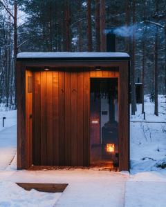 PunakiviÖÖD Hötels Laheranna SUME -with sauna的雪中带灯的木棚