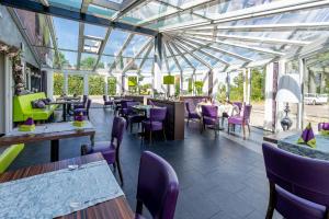 纽哈灵吉塞尔诺德斯特尔酒店的餐厅设有紫色椅子、桌子和窗户