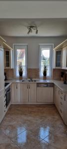 根尼斯迪亚斯Balaton Villa的一间设有白色橱柜和窗户的大厨房