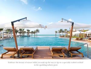 拉斯阿尔卡麦InterContinental Ras Al Khaimah Resort and Spa, an IHG Hotel的度假村的游泳池,配有椅子和遮阳伞