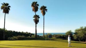 林孔-德拉维多利亚Añoreta Suites的两人在棕榈树高尔夫球场打高尔夫