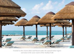 拉斯阿尔卡麦InterContinental Ras Al Khaimah Resort and Spa, an IHG Hotel的海滩上的一把稻草遮阳伞和椅子