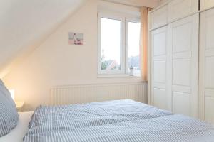 提努姆Haus Lia Rechts App 5的白色的卧室设有床和窗户