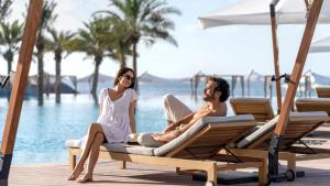 拉斯阿尔卡麦InterContinental Ras Al Khaimah Mina Al Arab Resort & Spa, an IHG Hotel的坐在游泳池畔躺椅上的男女