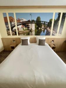 Mormant-sur-VernissonBrit Hotel Montargis的一张大白色床,享有桥梁的景色