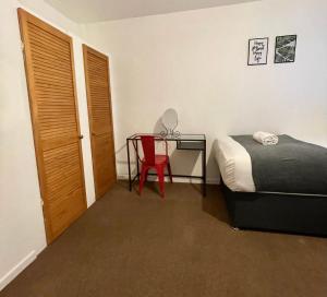 布里斯托Cheerful 5-bedroom with free parking的一间卧室配有一张床和一张带红色椅子的书桌