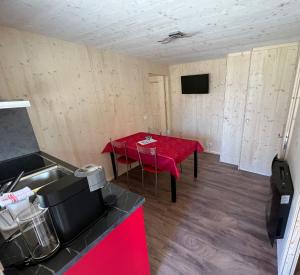波斯基亚沃Bungalow Miralago in Camping Cavresc, Via dal Cavresc 1, 7746 Le Prese-Poschiavo的一间设有一张桌子的房间,配有红色桌布