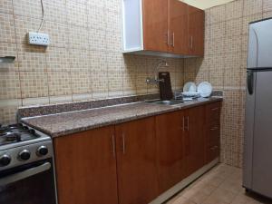 沙迦Furnished Apartment的厨房配有木制橱柜、水槽和冰箱。