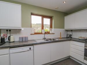 科尼斯顿Braeside的厨房配有白色橱柜、水槽和窗户。