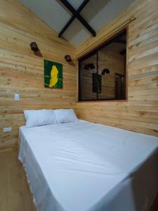 圣拉菲尔Cabaña Glamping Los Canarios San Rafael, Antioquia的木制客房内的一张白色大床,设有窗户