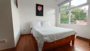 碧瑶RiCio Haus的一间卧室配有一张带白色床单的床和一扇窗户。