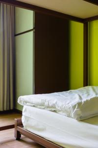 曼谷西亚梅子旅馆的两张未铺床,位于带绿色墙壁的房间内