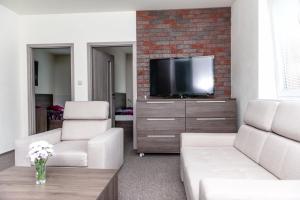 鲁容贝罗克哈勃沃酒店的客厅配有两把椅子和电视