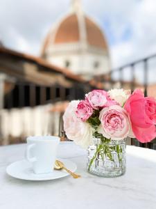 佛罗伦萨Duomo Suites Florence的粉红色玫瑰花瓶和咖啡