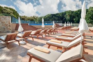 金沙GRIFID Hotel Foresta - All Inclusive & Free Parking - Adults Only的庭院里摆放着一排躺椅和遮阳伞