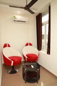 科钦Grace Apart Hotel @Kochi的两个红色的椅子和一张桌子