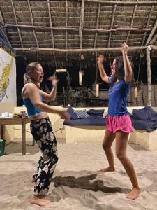 基林多尼Juani beach bungalows的两个女人在沙滩上跳舞