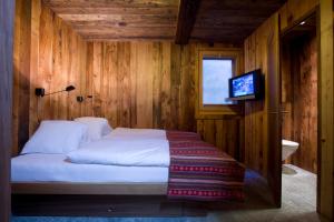 采尔马特兹高格瓦吉小木屋酒店的一间卧室配有一张床,里面配有电视
