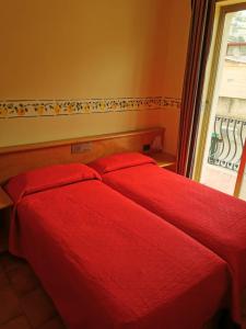 勒托阳尼Hotel San Pietro的卧室设有两张红色的床,卧室设有窗户