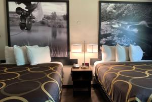 格里利格里利速8酒店的酒店客房设有两张床,墙上挂着一张照片。