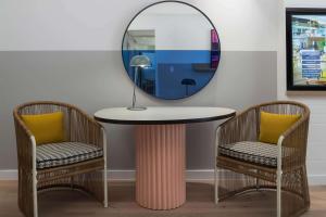 黄金海岸黄金海岸QT精品度假酒店的一张圆桌,配有两把椅子和镜子