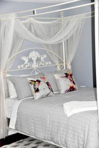 皮克图Seabank House Bed and Breakfast Hummingbird的白色的天蓬床,配有白色的窗帘和枕头