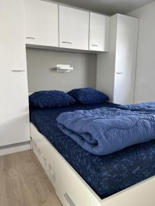 海牙Vakantiepark Kijkduin - 884的一间卧室配有一张带蓝色床单和白色橱柜的床。