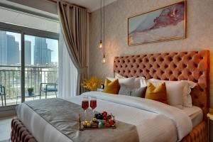 迪拜Durrani Homes - Modern Living at Burj Views的一间卧室配有一张大床,提供两杯葡萄酒