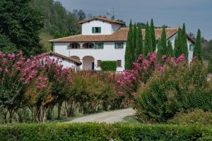 雷杰洛VIESCA Suites & Villas Il Borro Toscana的一条有粉红色花的马路中间的房子